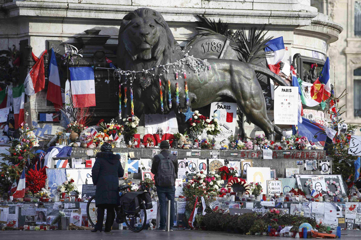 People at the Place de la Republique in Paris Jan. 6 look at flowers and messages paying tribute to the victims of last year's attacks at the office of the French weekly magazine Charlie Hebdo. (CNS/Charles Platiau, Reuters) 