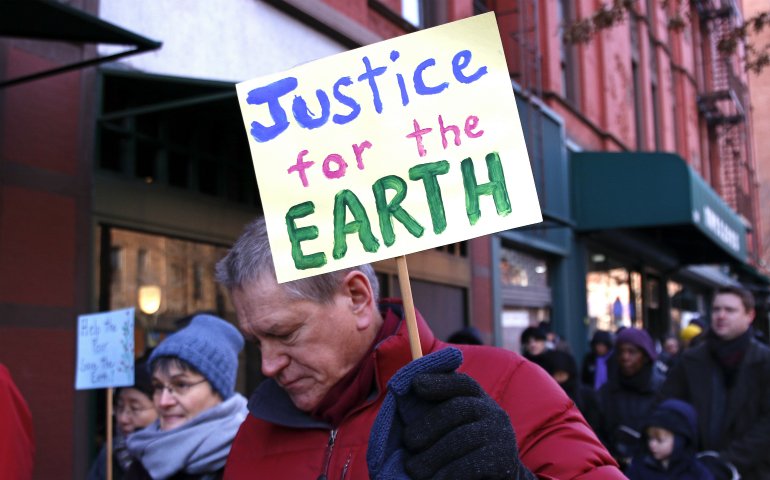 A man carries a sign during the annual Martin Luther King Jr. Day Interfaith Peace Walk Jan. 18, 2016, in New York City. Earth Day, observed April 22 every year, marks the anniversary of the birth of the modern environmental movement in 1970. (CNS/Gregory A. Shemitz)