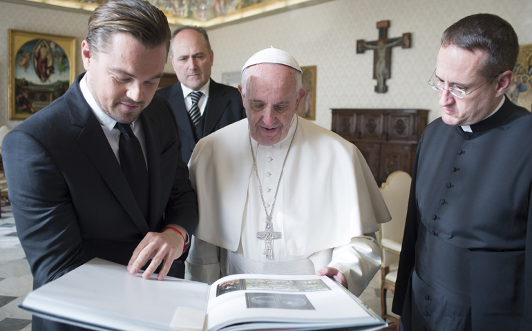 Leonardo DiCaprio and Pope Francis look at a book during their meeting in the Apostolic Palace at the Vatican Jan. 28. (CNS/L'Osservatore Romano, handout)