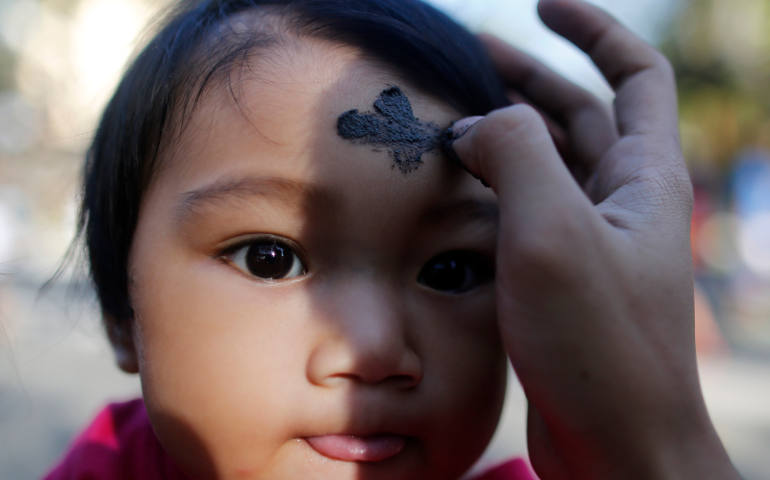 A seminarian marks a cross on the forehead of a child during Ash Wednesday Mass at a church in Manila, Philippines. (CNS photo/Francis R. Malasig, EPA)