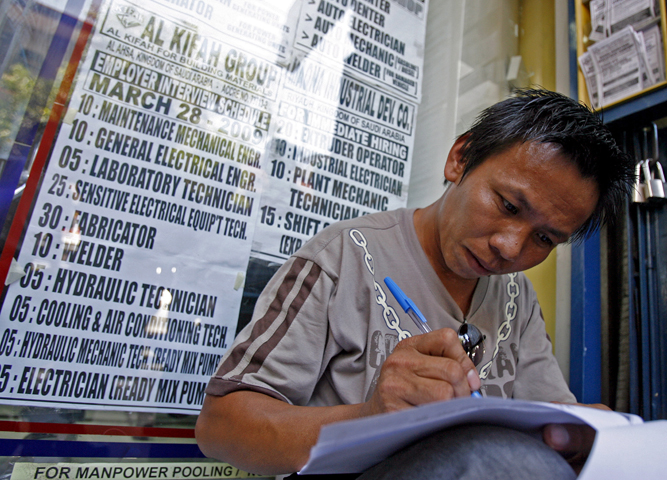 In this 2009 file photo, a Filipino jobseeker fills out forms outside a recruitment agency in Manila for jobs in the Middle East. (CNS/Alanah Torralba, EPA) 