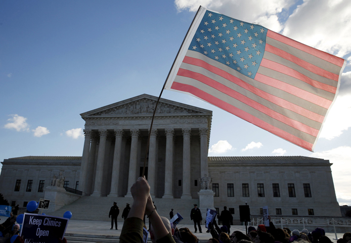 A person holds up the American flag in front of the U.S. Supreme Court in Washington March 2. (CNS/Kevin Lamarque, Reuters)