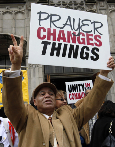 Robert Walker holds up a sign to cars outside St. Martin de Porres Church in Chicago May 1. Parishioners took to the streets to witness for peace in their neighborhood, which has experienced rising violence, after a Mass celebrated by Chicago Archbishop Blase Cupich. (CNS/Karen Callaway, Catholic New World)