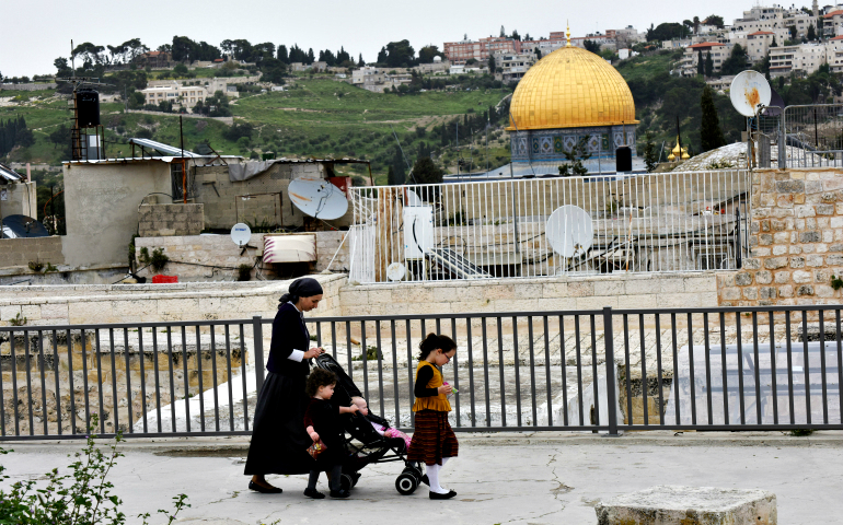 An Orthodox Jewish woman walks with her children on the roof in the Arab section of the Old City of Jerusalem on her way from an Israeli settlement March 26. (CNS/Debbie Hill)