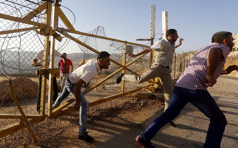 Palestinian men climb through a fence June 17 in an attempt to enter Jerusalem near the West Bank to attend the Friday prayers at the al-Aqsa Mosque. (CNS/EPA/Abed Al Hashlamoun)