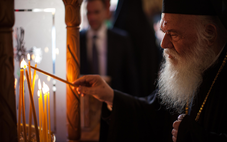 Orthodox Archbishop Ieronymos II of Athens and all of Greece lights a candle as he enters St. Mena Cathedral in Heraklion, Greece, June 19. The Great and Holy Council of the Orthodox Church opened June 19. (CNS/Sean Hawkey, handout)