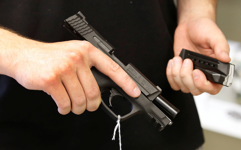 A salesman holds a Smith & Wesson handgun and magazine at the Ready Gunner gun store in Provo, Utah. (CNS/Reuters/George Frey)