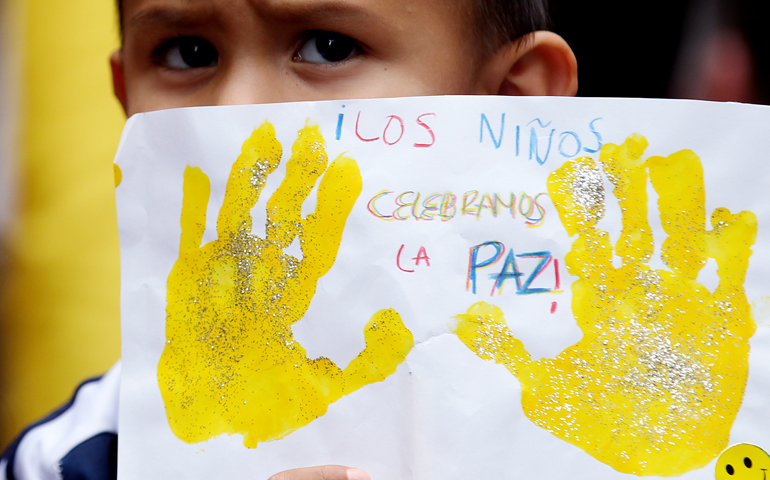 A boy in Bogotá, Colombia, June 23 shows his drawing, which reads "Children celebrate peace." (CNS/EPA/Leonardo Munoz)