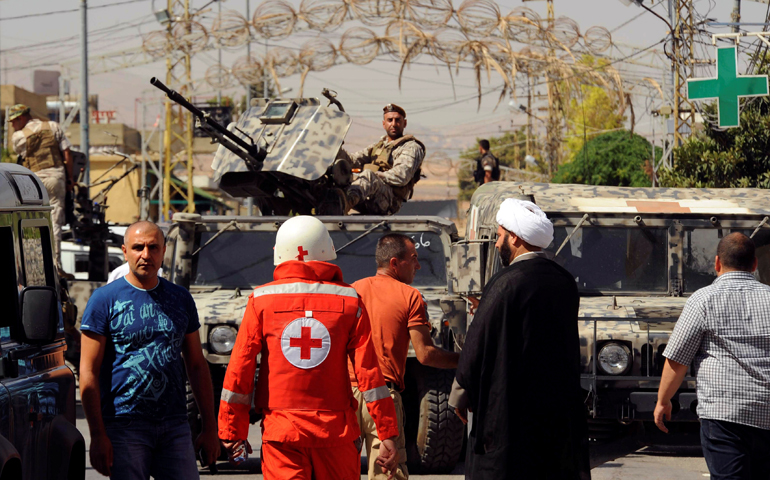 Lebanese army soldiers patrol as a Red Cross member walks near the site where suicide bomb attacks took place June 27 in the village of Qaa.(CNS/Hassan Abdallah, Reuters)