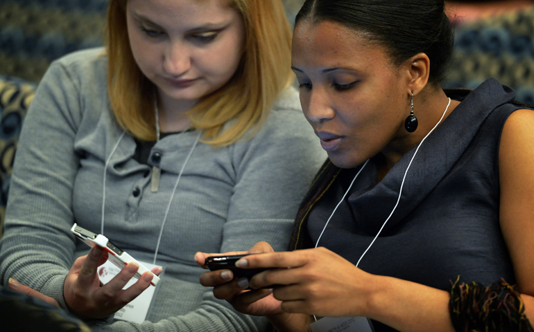 Young women tweet messages during a conference in Washington in a 2012 file photo. (CNS/Paul Jeffrey)