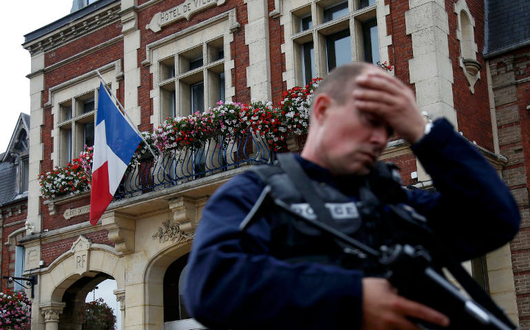 A policeman reacts as he secures a position in front of city hall after two assailants killed 84-year-old Fr. Jacques Hamel and took five people hostage during a weekday morning Mass at the church in Saint-Etienne-du-Rouvray, France, near Rouen July 26. (CNS photo/Pascal Rossignol/Reuters)