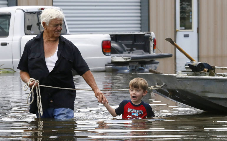 Richard Rossi and his 4-year-old great-grandson Justice wade through water Aug. 15 after their home flooded in St. Amant, La. (CNS photo/Jonathan Bachman, Reuters)