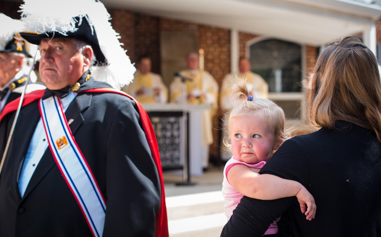 Fifteen-month-old Charlotte Kerscher, held by her mother, Laura, watches the Knights of Columbus honor guard process during an outdoor Mass at the National Shrine of Our Lady of Good Help in Champion, Wis., Aug. 15, 2016 (CNS/Sam Lucero, The Compass)