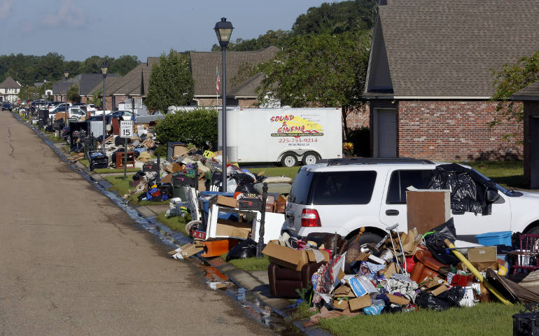 Residents pile debris outside their flood-damaged homes in St. Amant, La., Aug. 21. (CNS photo/Jonathan Bachman, Reuters)