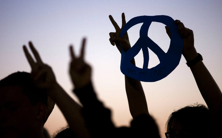 Protesters raise their hands with peace signs after a string of nationwide police shootings of African-Americans and the slaying of police officers in Dallas during a July 8 vigil in Huntington Beach, Calif. (CNS photo/Eugene Garcia, EPA) 