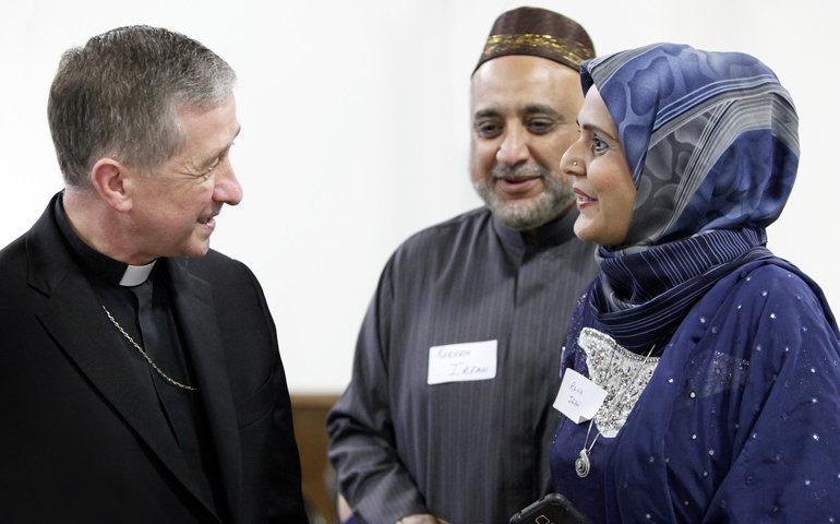 Chicago Archbishop Blase Cupich visits with a couple during a June 27 Catholic-Muslim dinner in Bridgeview, Ill.