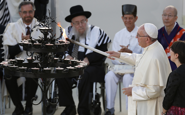 Pope Francis lights a candle during an interfaith peace gathering Sept 20 outside the Basilica of St. Francis in Assisi, Italy. (CNS/Paul Haring)