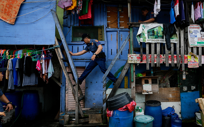 A Philippine police officer moves between houses in Manila during an operation against illegal drugs Oct. 6, 2016. (CNS/Mark R. Cristino, EPA)