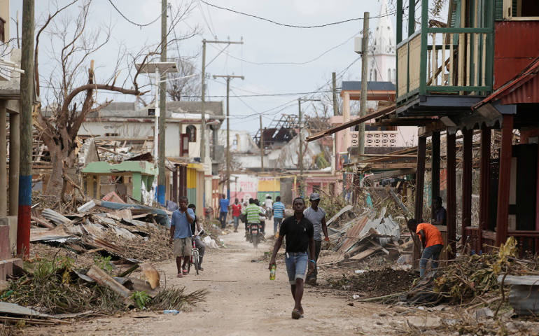 People walk past damaged buildings Oct. 9 after Hurricane Matthew swept through Port-a-Piment, Haiti. (CNS photo/Andres Martinez Casares, Reuters) 