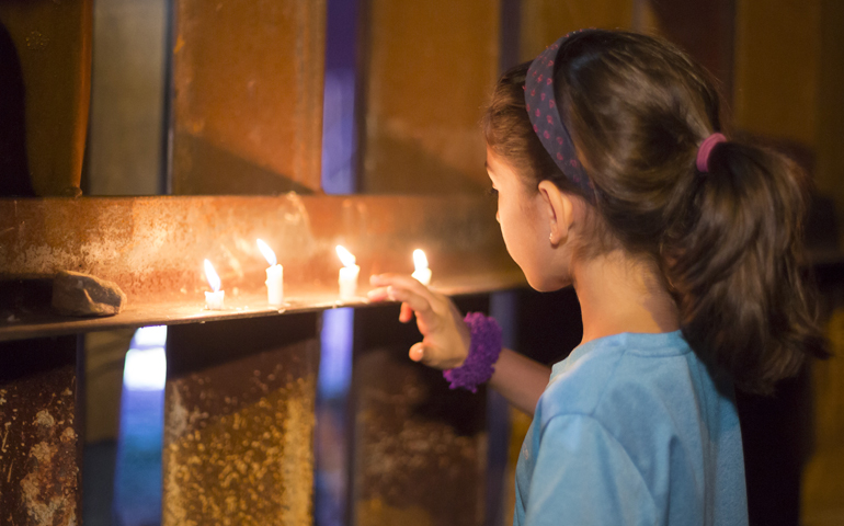 A girl looks at candles placed on the U.S.-Mexico border fence during an Oct. 8 interfaith protest against what activists say is an increasing militarization of the border. (CNS/Jim West)