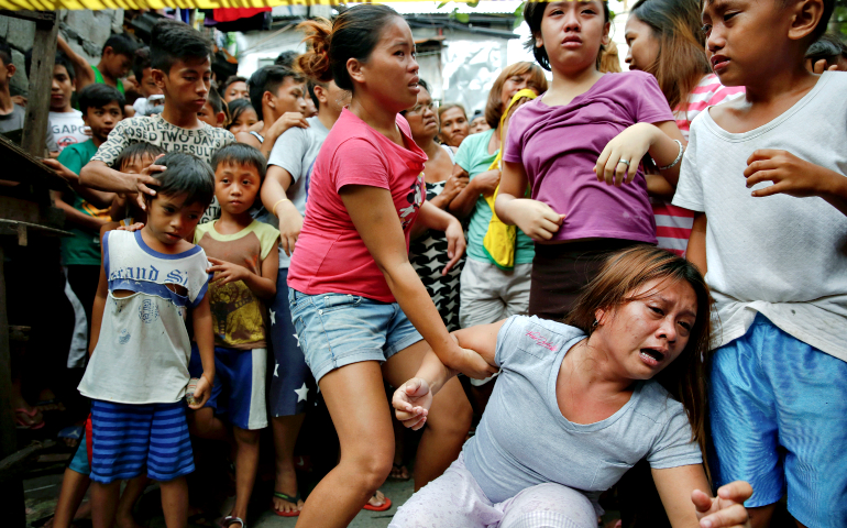 Janeth Mejos reacts as the body of her father is taken out of their home shortly after he was killed in a police operation in Manila, Philippines, Oct. 14. (CNS/Reuters/Damir Sagolj)