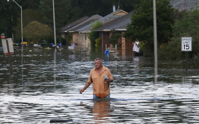 A man wades through a flooded street in Ascension Parish, La., Aug. 15. (CNS/Jonathan Bachman/Reuters)
