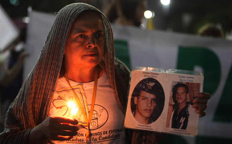 A woman holding a candle and images of disappeared victims takes part in a rally for peace Oct. 7 in Medellin, Colombia.