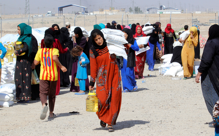 People who fled the Islamic State's strongholds of Hawija and Mosul receive aid Oct. 13 at a camp for displaced people in Daquq, Iraq. (CNS/Ako Rasheed, Reuters)