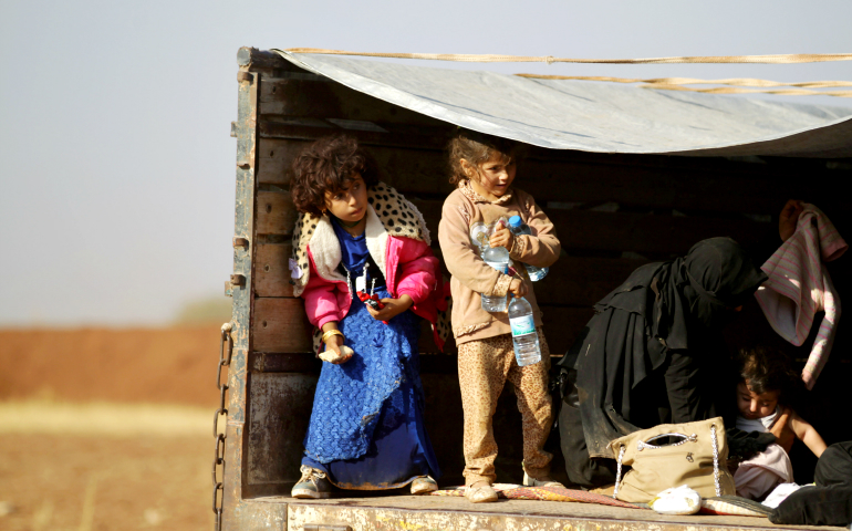 Iraqi refugees who fled violence in Mosul ride in a pickup truck Oct. 24 as they arrive in Aleppo, Syria. (CNS/Khalil Ashawi, Reuters)