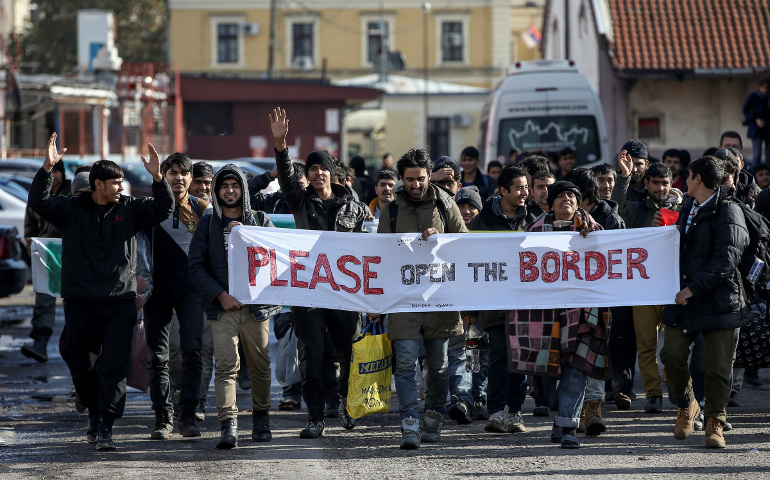 Refugees and migrants hold a banner and shout slogans Nov. 11 as they walk toward the Croatian border in Belgrade, Serbia. (CNS/Marko Djurica, Reuters)