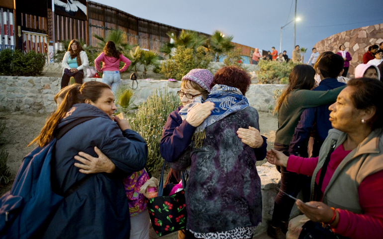 People hug during a Nov. 19, 2016, Mass near the U.S.-Mexico border fence in Tijuana, Mexico. The Mass and a procession with a statue of Our Lady of Guadalupe were a call to remember and pray for migrants. (CNS/David Maung)