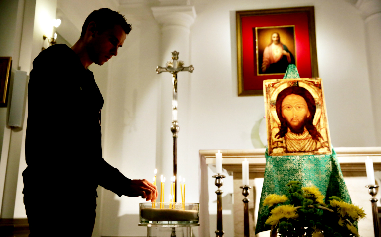 A man lights a candle during a prayer for peace in late October at a church in Warsaw, Poland. (CNS/EPA/Tomasz Gzell)