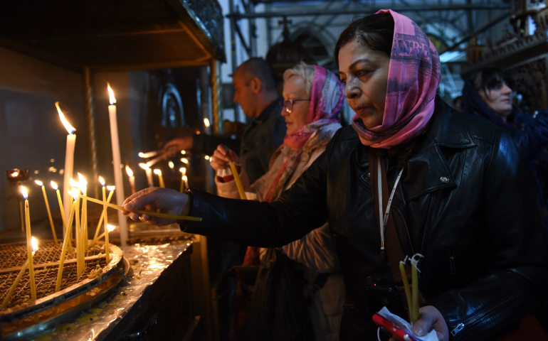 A pilgrim lights a candle Dec. 17 in the grotto of the Church of Nativity in Bethlehem, West Bank. (CNS photo/Debbie Hill)