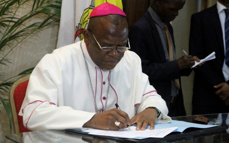 Congolese Bishop Fridolin Ambongo Besungu signs the accord between the opposition and the government of President Joseph Kabila Dec. 1 at the bishops' conference in Kinshasa. (CNS photo/Kenny Katombe, Reuters)