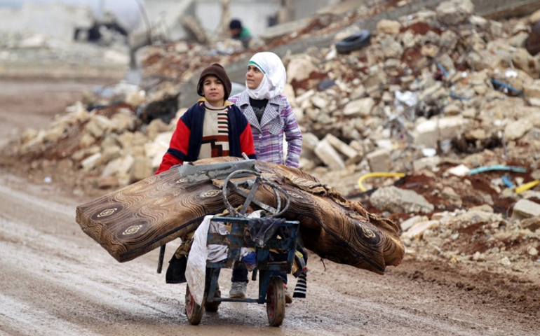 Syrian children transport their salvaged belongings from their damaged house in Doudyan, a village in northern Aleppo Jan. 2. (CNS/Khalil Ashawi, Reuters)