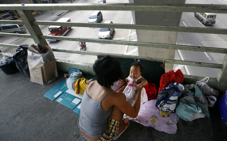 A mother holds her daughter in 2014 on a footbridge in Manila, Philippines. The Philippine president's executive order that the government begin distributing free contraceptives to the poor by 2018 may face delays because of a pending case before the country's Supreme Court. (CNS photo/Ritchie B. Tongo, EPA)