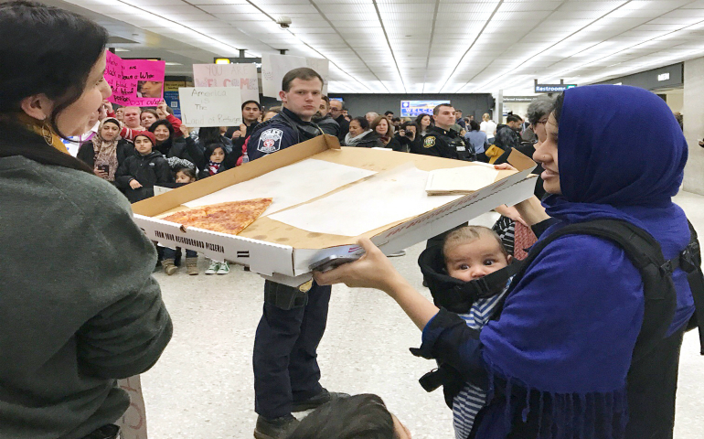 A woman offers pizza to people protesting the travel ban imposed by President Donald Trump at Washington Dulles International Airport in Dulles, Va., Jan. 28. (CNS photo/Yeganeh Torbati, Reuters)