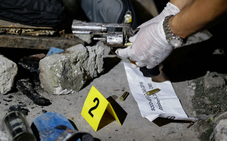 A Philippine crime scene investigator inspects a gun used in a 2016 murder in Novaliches. A Philippine cardinal has urged the faithful of his country to tell their lawmakers that the death penalty does not deter violent crime, could potentially legitimize violence and that life is a gift from God. (CNS photo/Mark A. Cristino, EPA)