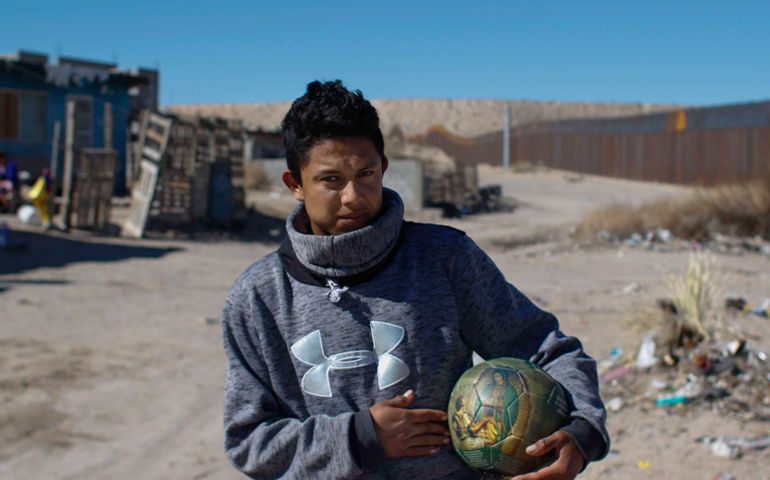 A young man holds a soccer ball with an image of Our Lady of Guadalupe Jan. 26 in Ciudad Juarez, Mexico, near the U.S.-Mexico border fence. (CNS/Alejandro Bringas, EPA)