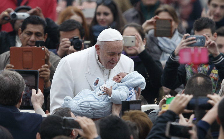 Pope Francis greets a baby during his general audience in St. Peter's Square at the Vatican Feb. 22. (CNS photo/Paul Haring)