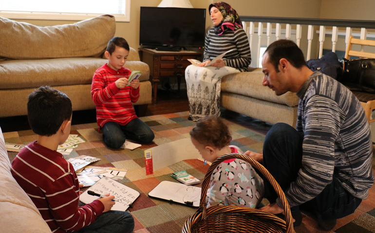Syrian refugees Ahmed Al Kango and his wife, Sahar, help their children learn English Feb. 7 in their home in Elkhorn, Neb. Pictured from left, the children are Mohamad, Ghaith and Abdulrazzaq. (CNS/Joe Ruff, Catholic Voice)