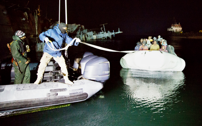 Libyan Coast Guard personnel pull an inflatable boat carrying immigrants at the Port of Tripoli, Libya, Feb. 4. (CNS/EPA)