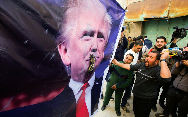 A Palestinian demonstrator throws a shoe at a poster depicting U.S. President Donald Trump during a protest in the West Bank city of Hebron Feb. 24. (CNS/Mussa Qawasma, Reuters)