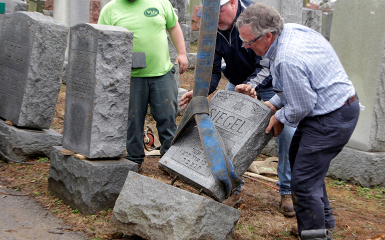 Men work to right toppled Jewish headstones Feb. 21 after a vandalism attack on Chesed Shel Emeth Cemetery in University City, Mo. (CNS/Tom Gannam, Reuters)