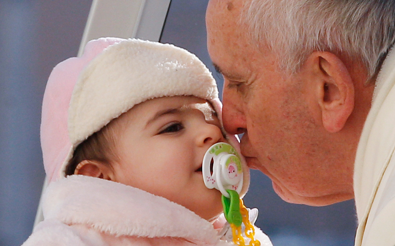 Pope Francis kisses a baby during a general audience in St. Peter's Square Dec. 18, 2013. March 13 marked the fourth anniversary of the Argentine cardinal's election as pope. (CNS/Paul Haring)