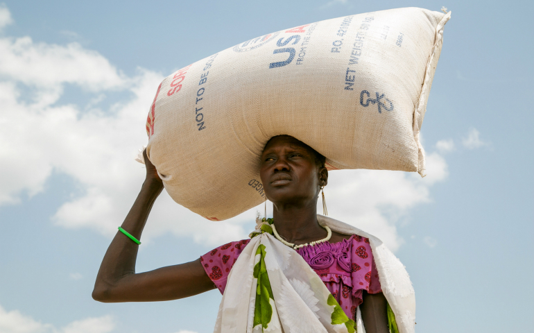 A woman carries food provided by U.S. Agency for International Development in Pajut, South Sudan, March 17. (CNS/Catholic Relief Services/Nancy McNally)