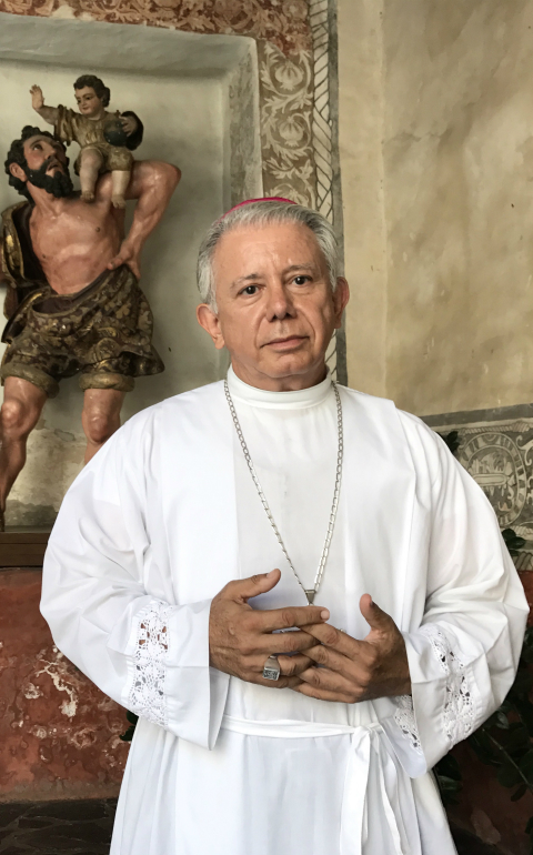 Bishop Ramon Castro Castro of Cuernavaca, Mexico, poses March 26 in the Assumption of Mary Cathedral in front of an image of St. Christopher from the colonial period. (CNS photo/David Agren)