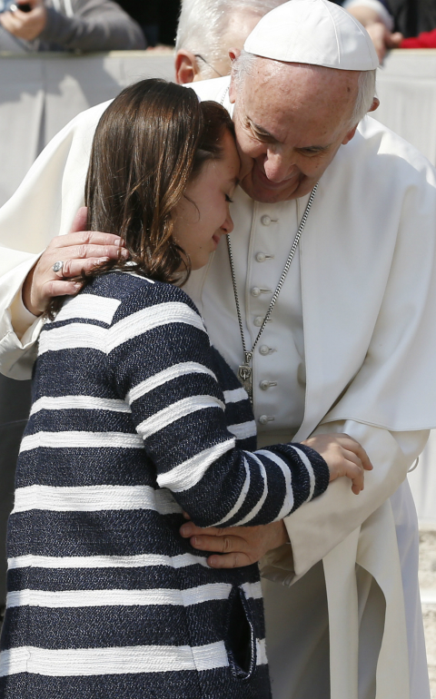 Pope Francis embraces a girl during his general audience in St. Peter's Square at the Vatican April 5. The pope strongly condemned a chemical attack in Syria the previous day that left 70 people dead. (CNS photo/Paul Haring)