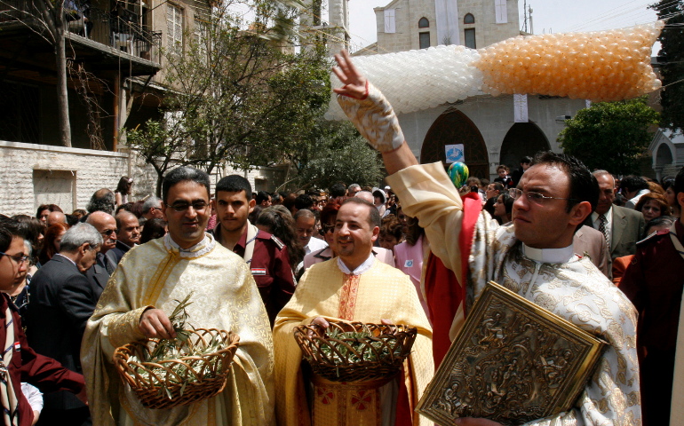 Clergymen throw olive branches April 9 during Palm Sunday celebrations outside Our Lady of Fatima Church in Damascus, Syria. (CNS/Youssef Badawi, EPA)