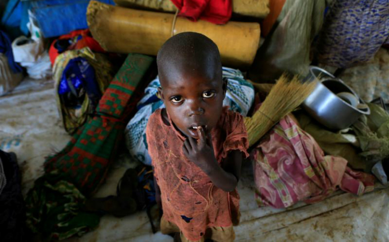 A boy from South Sudan stands next to his family's belongings April 5 at a camp for displaced people in Lamwo, Uganda. (CNS photo/James Akena, Reuters)